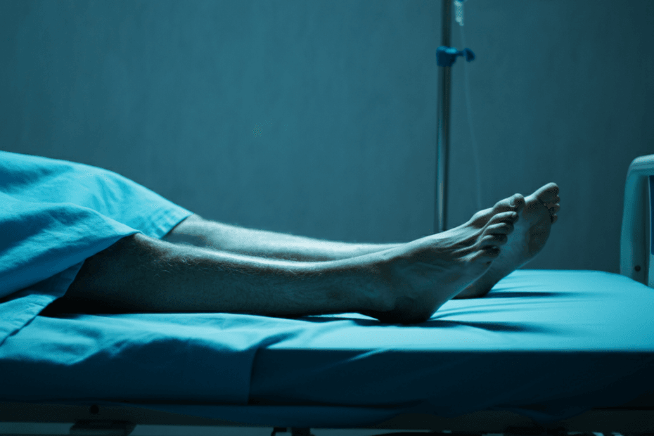 A blue theme image of the legs of an human laid on a hospital bed